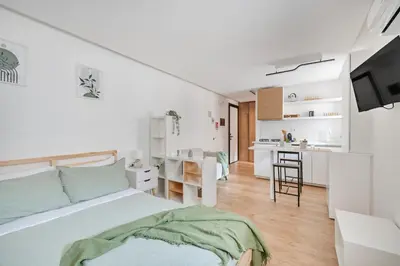 a white bedroom with a bed and a kitchen at NOH Vatican Studio in Rome