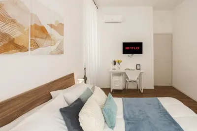 a white bedroom with a bed and a desk at Vaticano Domvs - Appartamento ai Musei Vaticani in Rome