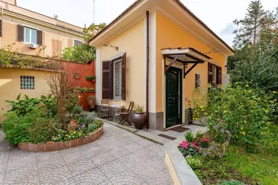 a yellow house with a black door and some flowers at Cottage San Giovanni in Rome