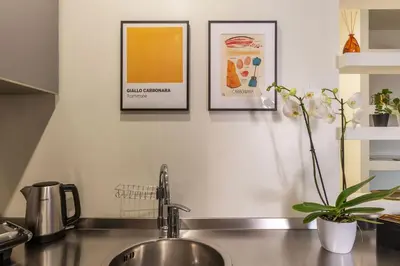 a kitchen counter with a sink and two pictures on the wall at GuestHost - Aurea Domus Comfort suite in centro a Roma in Rome
