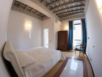 a bedroom with a white bed and a chair at Campo Marzio Charming in Rome
