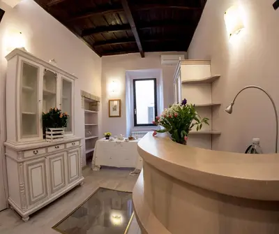 a kitchen with white cabinets and flowers in a room at Campo Marzio Charming in Rome