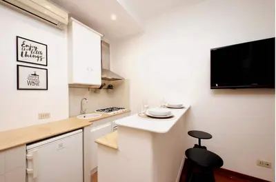 a small white kitchen with a black stool in it at La Dolce Vita - Vatican Studio with Large Terrace in Rome