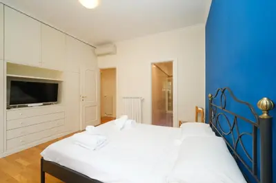 a bedroom with two white beds and a blue wall at Juan&Elisa Trevi by BuddyRent in Rome