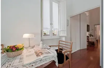 a living room with a table with a newspaper and flowers at B&B Colori di Roma in Rome