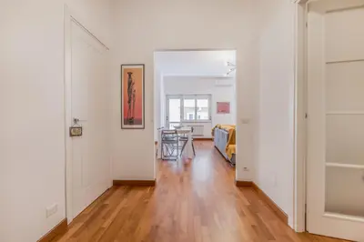 a hallway with white walls and wood floors and a room with a table at Zampieri Loft in Rome
