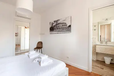 a white bedroom with a bed and a chair at Luminoso Attico Piazza Bologna - Metro Policlinico in Rome