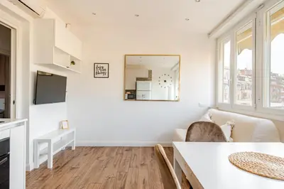 a white living room with a table and a mirror at Luminoso Attico Piazza Bologna - Metro Policlinico in Rome