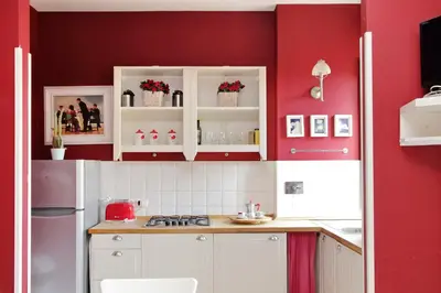 a kitchen with red walls and white cabinets at 6 People Apartment at Vatican in Rome