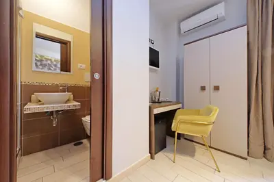 a bathroom with a yellow chair and a sink at Roma Suite Centro in Rome