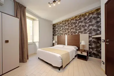 a bedroom with a white bed and a stone wall at Roma Suite Centro in Rome
