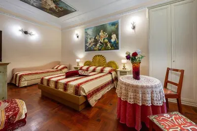 a bedroom with two beds and a table and a painting at Sancta Scala in Rome
