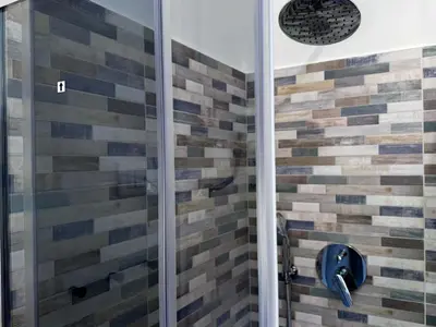 a shower with wooden tiles on the wall at JHHIT - Panoramic Modern Penthouse in Rome