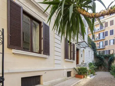 a building with shuttered windows and a palm tree at Apartment Plinio by Interhome in Rome