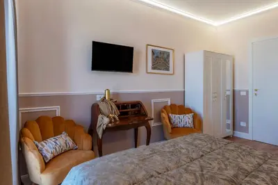 a bedroom with a bed and two chairs and a tv at YCH-Ponte Lungo apartment in Rome