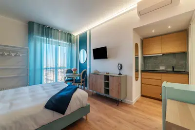 a bedroom with a large bed and a kitchen at YCH-Ponte Lungo apartment in Rome