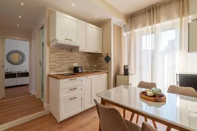a kitchen with white cabinets and a table with chairs at YCH-Ponte Lungo apartment in Rome