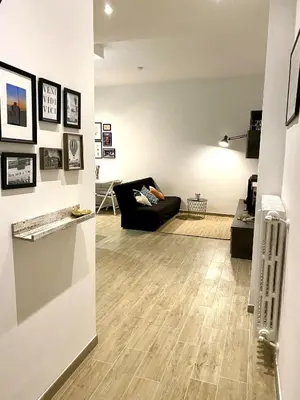 a living room with a black couch and wooden floors at a pochi passi dalla Metro A e dal Vaticano - NUMA HOUSE in Rome