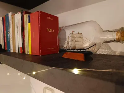 a bottle with a ship in it next to books at a pochi passi dalla Metro A e dal Vaticano - NUMA HOUSE in Rome