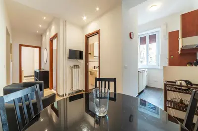 a kitchen and living room with a glass table and chairs at GuestHost - Piazza Bologna Apartment in Rome