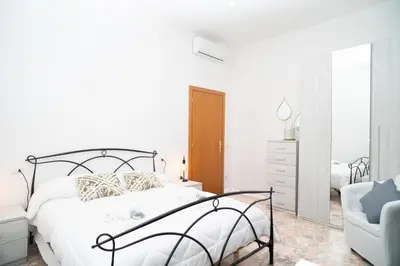 a white bedroom with a bed and a chair at Minimal e funzionale soggiorno vicino al Vaticano in Rome