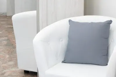 a white chair with a gray pillow on it at Minimal e funzionale soggiorno vicino al Vaticano in Rome