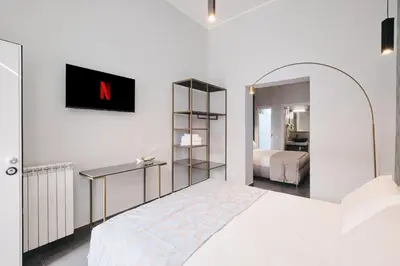 a bedroom with a white bed and a mirror at Domus Matris Guest House in Rome