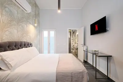 a bedroom with a white bed and a tv on a wall at Domus Matris Guest House in Rome
