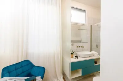 a bathroom with a blue chair and a sink at Moon River Luxury Apartment in Rome
