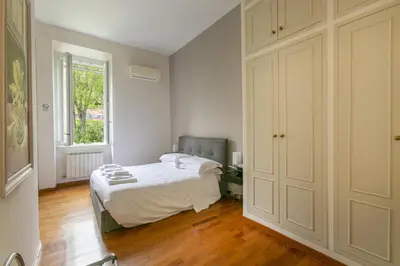 a white bedroom with a bed and a window at Family Stay in Trastevere in Rome