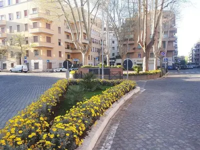 a row of yellow flowers on a street with buildings at New Jebs sweet home Rome in Rome