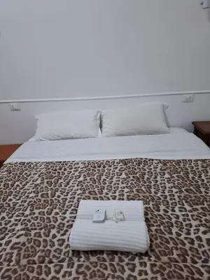 a bed with a white blanket and two shoes on it at AFFITTACAMERe ROME PALACE in Rome