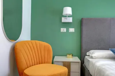 an orange chair sitting next to a bed in a room at Marconi APT per Famiglie - 20 Min dal centro in Rome