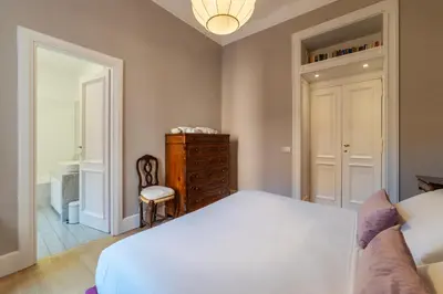 a bedroom with a white bed and a chair at Santa Maria alle Fornaci - FromHometoRome in Rome