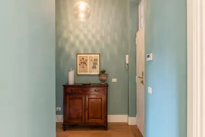 a hallway with a wooden cabinet and a blue wall at Santa Maria alle Fornaci - FromHometoRome in Rome