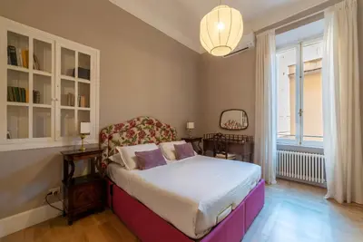 a bedroom with a bed with a chair and a window at Santa Maria alle Fornaci - FromHometoRome in Rome