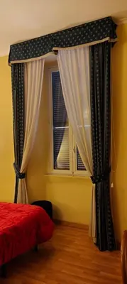 a bedroom with a bed and a window with curtains at Soggiorno Fenicia in Rome