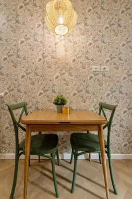 a wooden table with two green chairs and a potted plant at Amelie - Gem of Trastevere in Rome