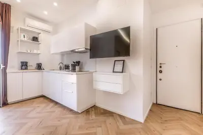 a kitchen with white cabinets and a flat screen tv at Domvs Romana in Rome