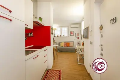 a kitchen with red and white cabinets and a living room at La Torre Della Scimmia nido romantico a Piazza Navona in Rome