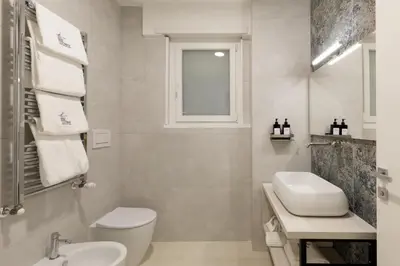 a white bathroom with a toilet and a sink at Cosmo Vatican Rooms in Rome