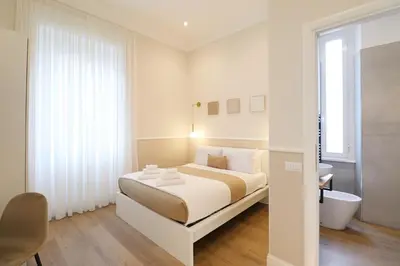 a white bedroom with a bed and a bathroom at St Peter & Vatican Luxury Suites - Boutique Suites in Rome Centre & Vatican - AC, Wifi & Metro 5 min in Rome