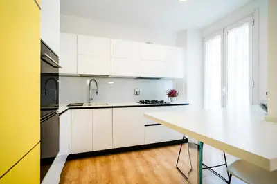 a kitchen with white cabinets and a white counter top at San Giovanni Art Apartment in Rome