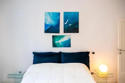 a bedroom with a bed with three paintings on the wall at San Giovanni Art Apartment in Rome