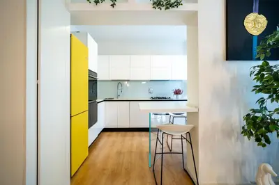 a kitchen with white cabinets and a table and stools at San Giovanni Art Apartment in Rome