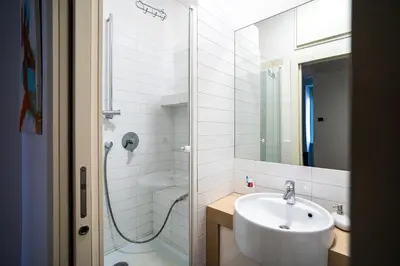 a white bathroom with a sink and a shower at San Giovanni Art Apartment in Rome
