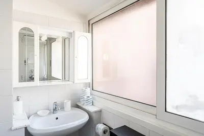 a white bathroom with a sink and a window at Piazza Navona the most central apartment in Rome