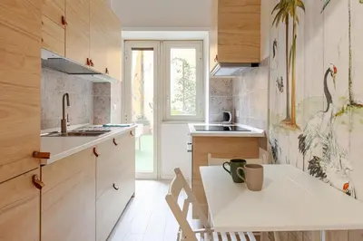 a kitchen with wooden cabinets and a white table and chairs at Casa d' artista Margot in Rome