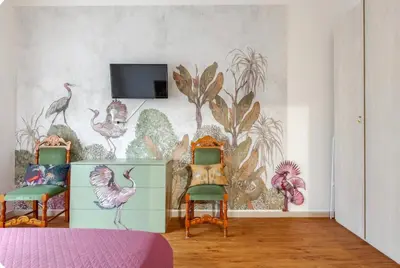 a room with two chairs and a mural of birds at Casa d' artista Margot in Rome