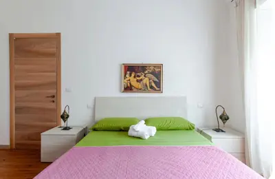 a bedroom with a bed with a pink and green blanket at Casa d' artista Margot in Rome